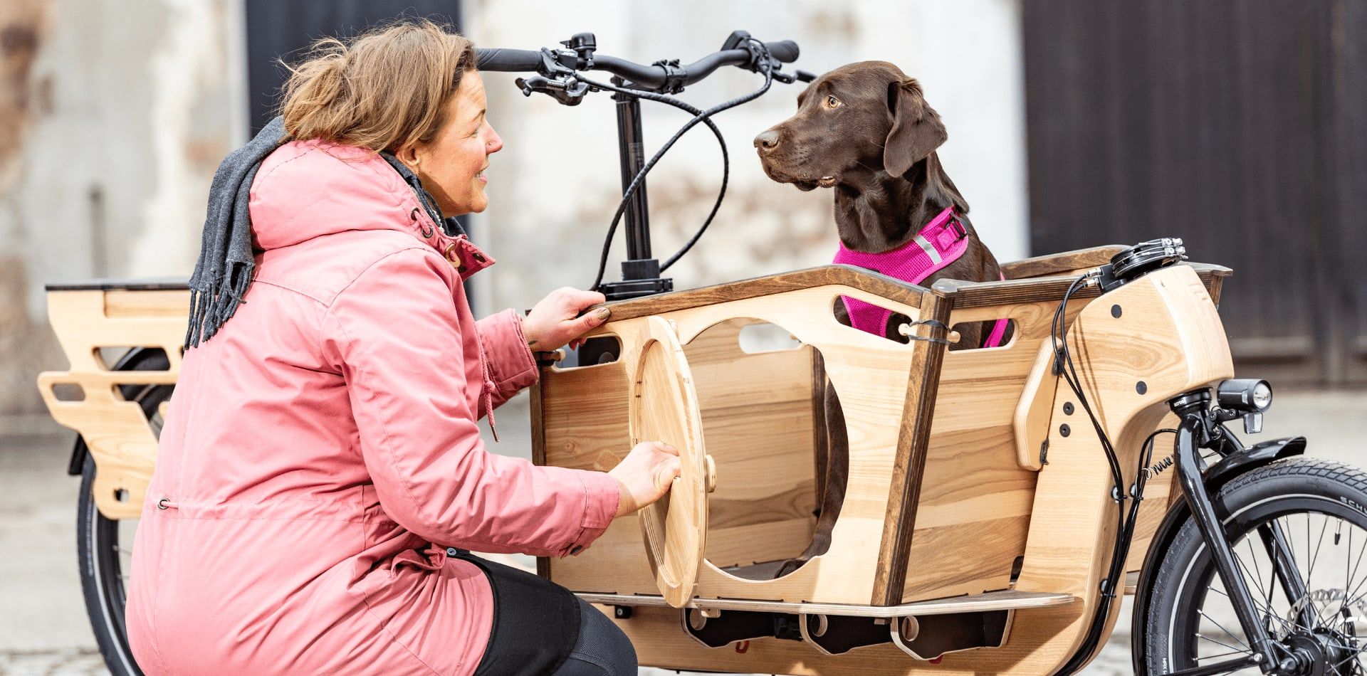 Frau mit Hund in der Transportbox des Lastenrads