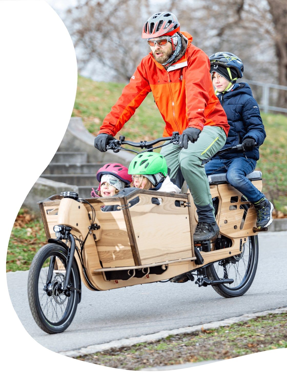 Vater fährt mit drei Kindern auf dem Holzlastenrad LJ215